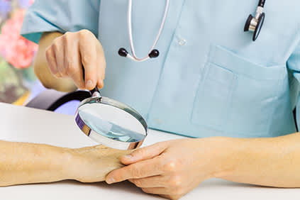 皮肤科医生用放大镜来检查女性的皮肤。