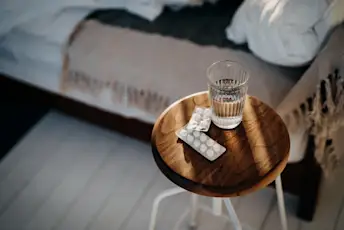 白色药丸和一杯水在床旁的床头柜上