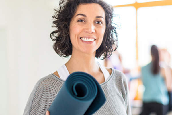 女子抱着一个瑜伽垫。