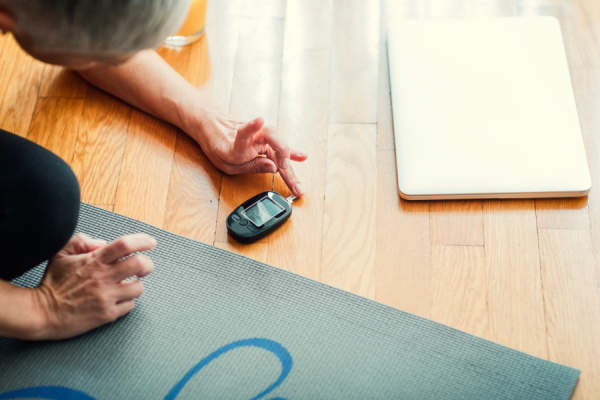 成熟的女人在瑜伽垫上做血糖测试