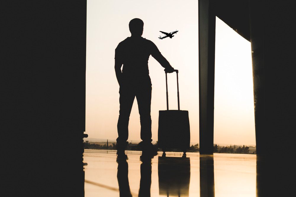 男子的剪影与手提箱看着飞机
