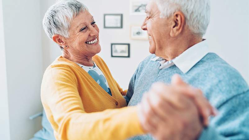 Smiling senior couple dancing at home.