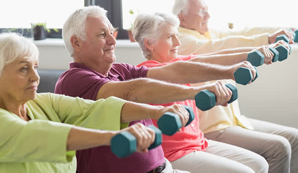 老年人在健身课上练习举重。