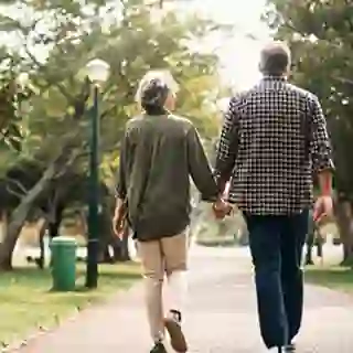 Senior couple walking through a park holding hands.