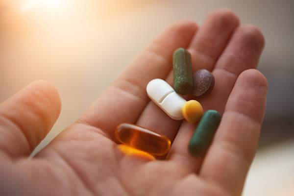 Hand holding many dietary supplement pills
