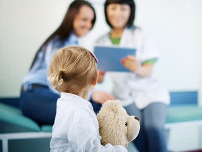 小女孩抱着泰迪熊去看医生。