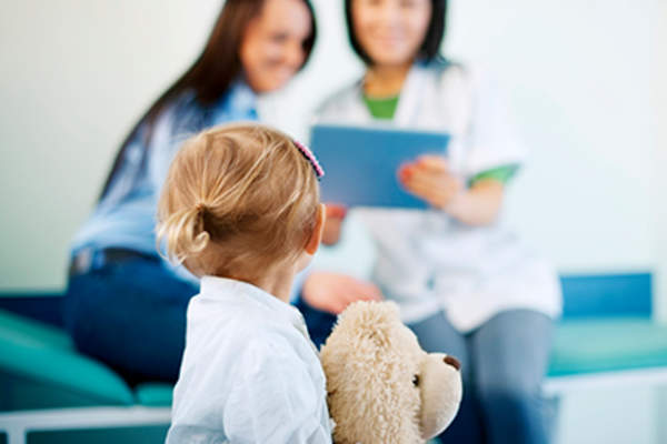 小女孩抱着泰迪熊去看医生。