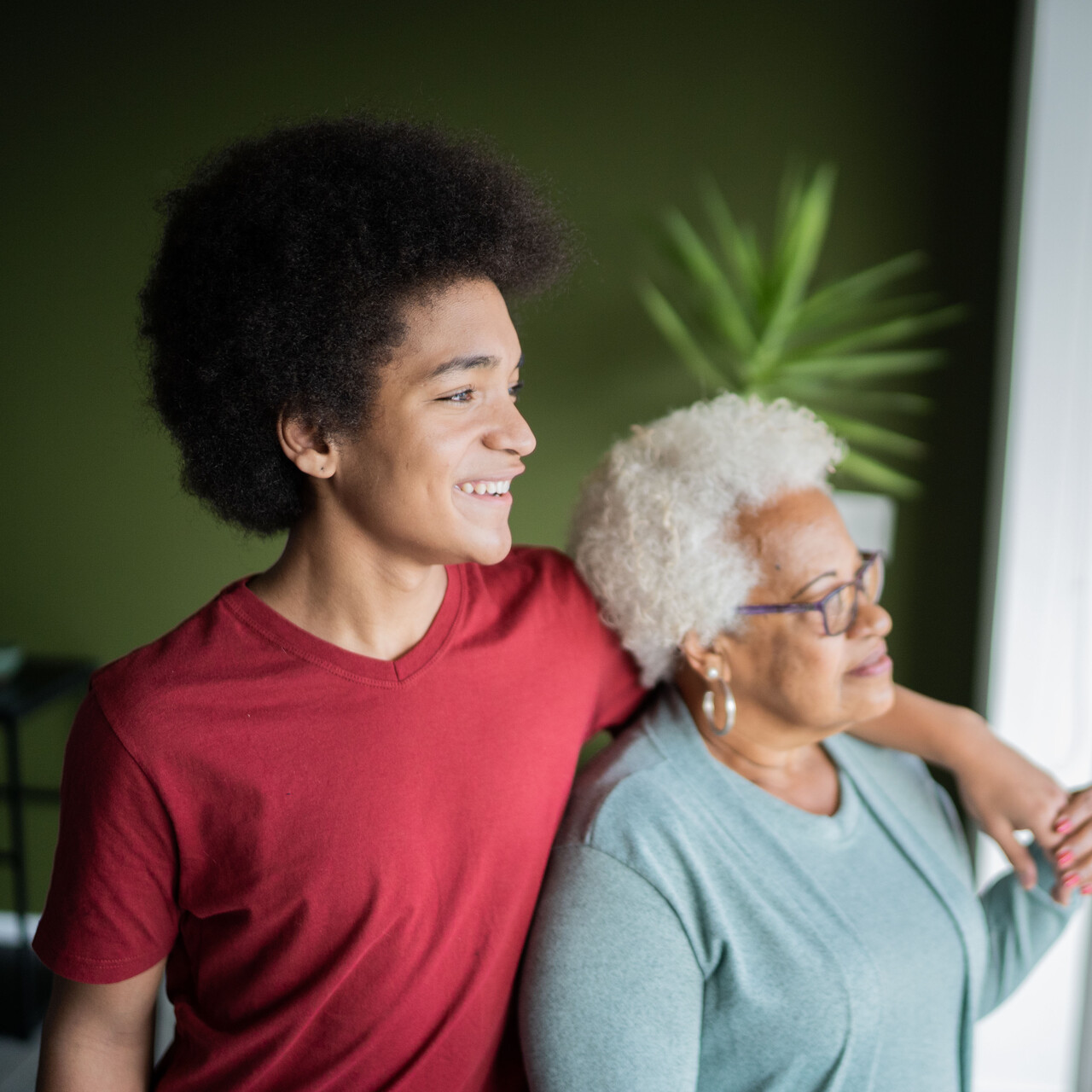 十几岁的男孩和他的祖母微笑在家里。