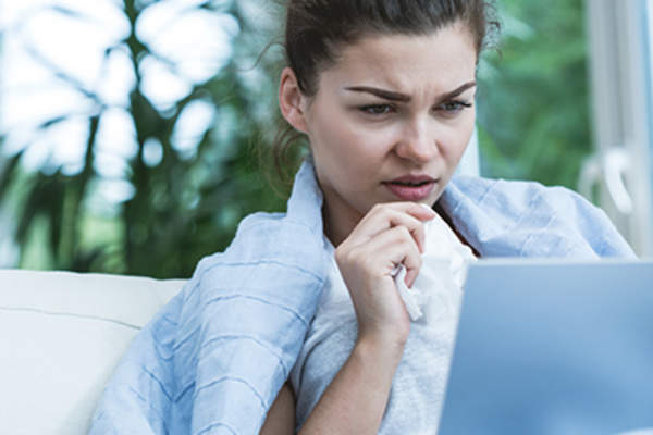 生病的女人在床上用笔记本电脑工作。