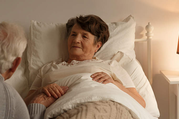 高级丈夫抱着生病的妻子的手。