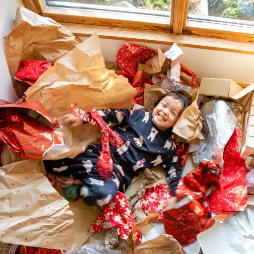 一个孩子躺在一堆礼品包装纸中的景色