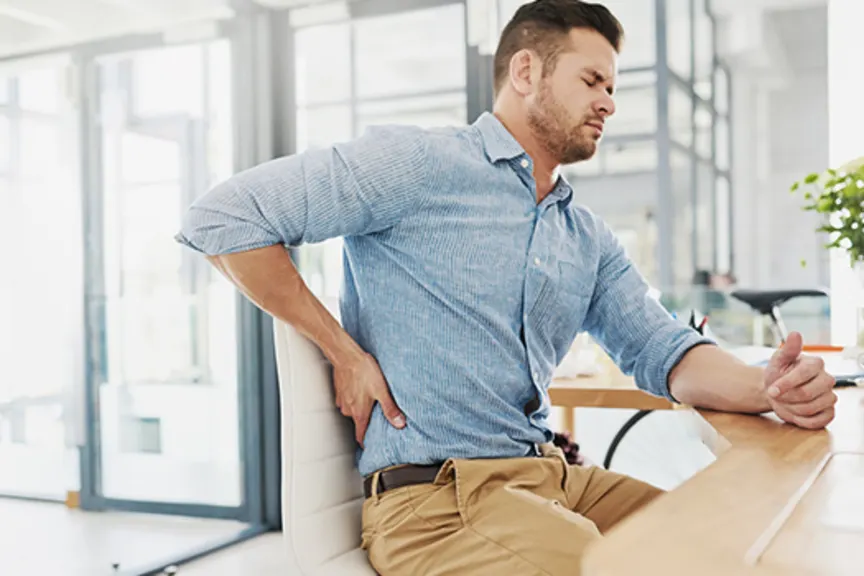 Man sitting in an office with lower back pain.