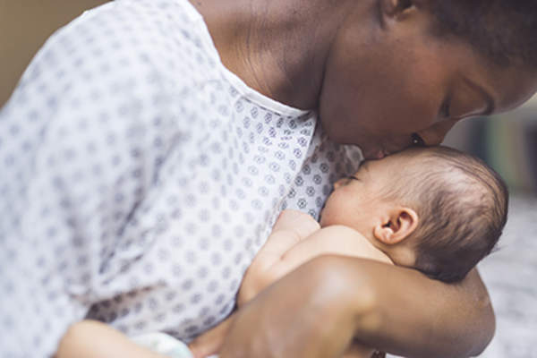 Woman kissing her newborn baby.
