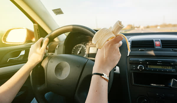 女人吃了香蕉而驾驶的图像。