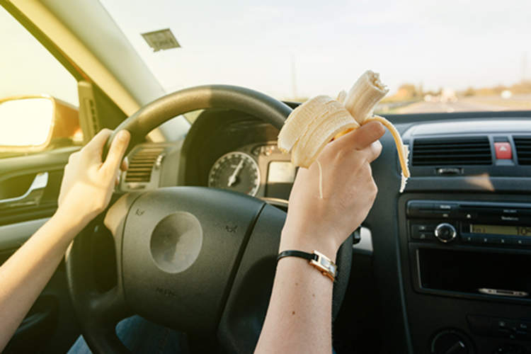 女人吃了香蕉而驾驶的图像。