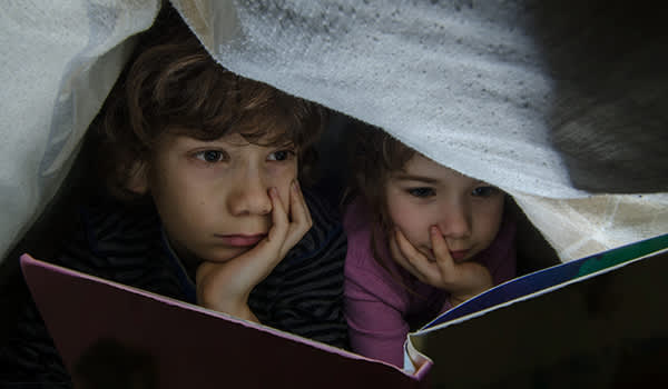 孩子们在毯子下阅读。
