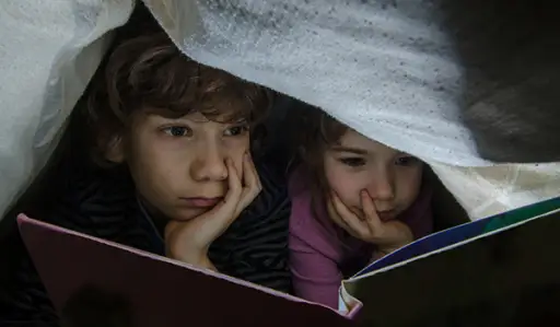 孩子们在一张毯子下阅读。