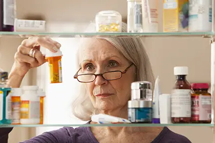 女人从她的药柜里看一瓶。