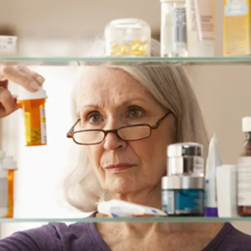 一个女人看着药柜里的药瓶。