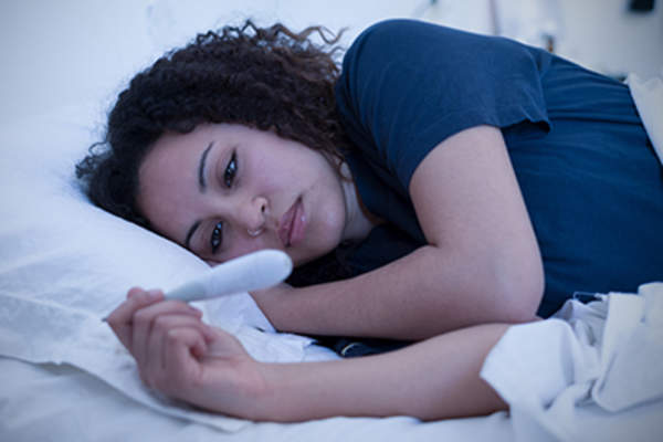 女人在床上量体温。