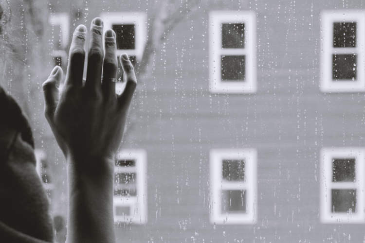 手的黑白照片对窗口在雨中