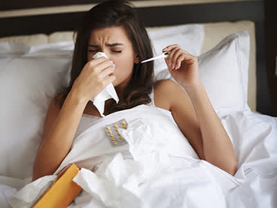 一个女人躺在床上，流着鼻涕，还发烧。