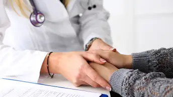 医生抱着女性患者的手。