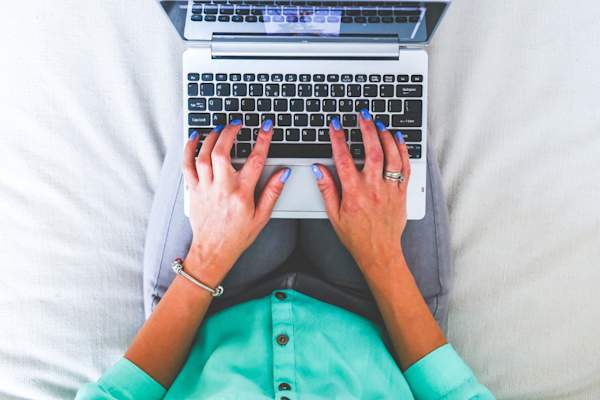 坐在床上用笔记本电脑打字的女人