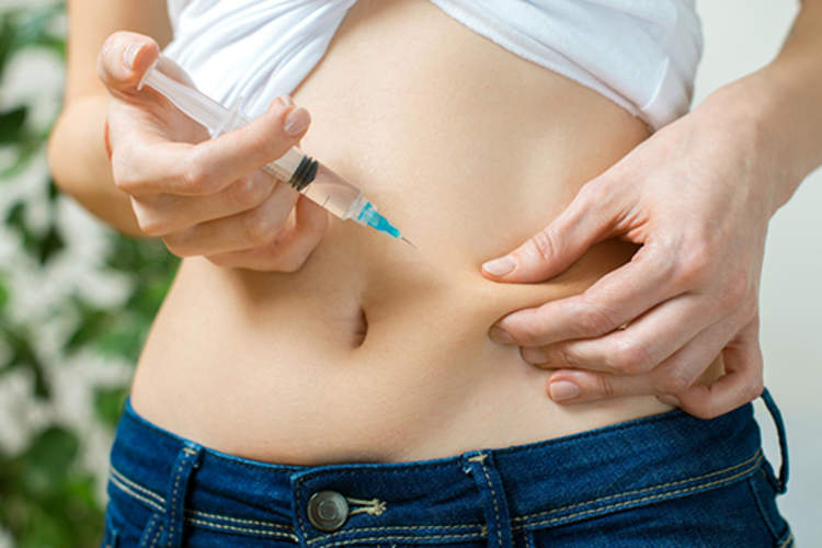 一位年轻女子在腹部给自己打了一针。