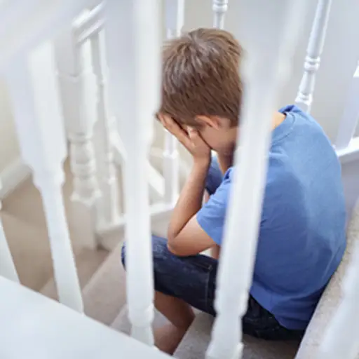 创伤的小男孩在楼梯上哭泣。