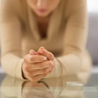 Closeup on the hands of a stressed person leaning on a table
