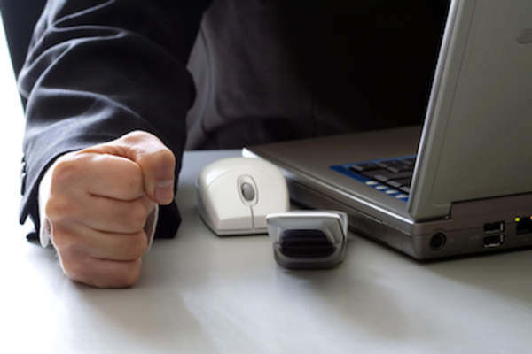 坐在电脑前的人,一只手紧握成拳头