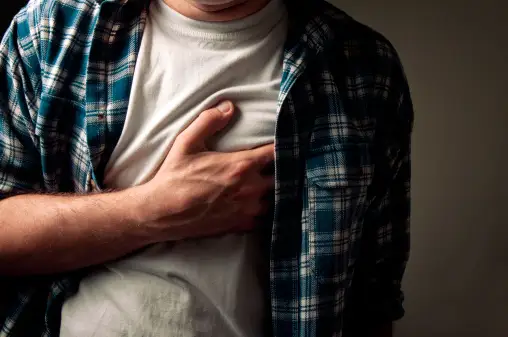 男人在经历剧烈的疼痛时紧紧抓住胸部。