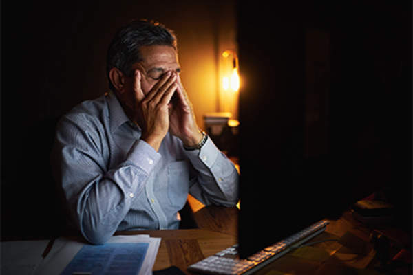 有压力的人晚上在电脑前工作。