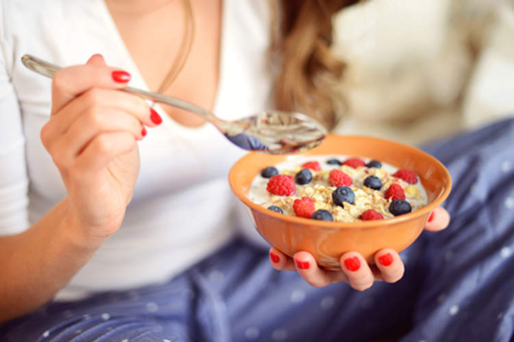 一个穿着睡衣的女人在卧室里吃着草莓什锦早餐。