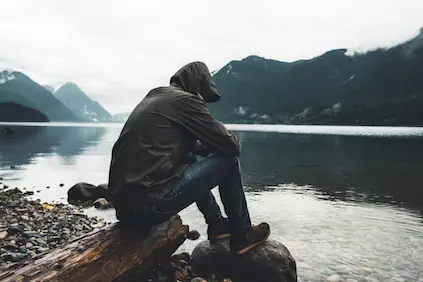 一个沮丧的男人坐在河岸上