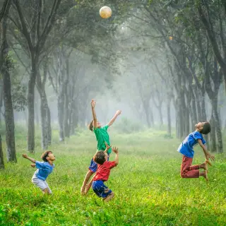 four boys jumping and playing with ball