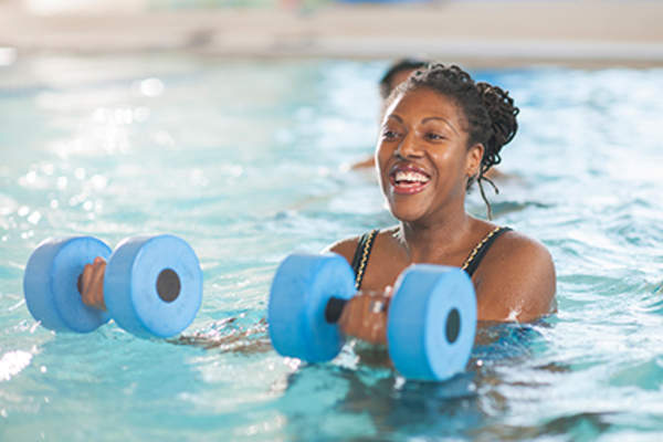 Woman doing water aerobics to ease her symptoms of RA.