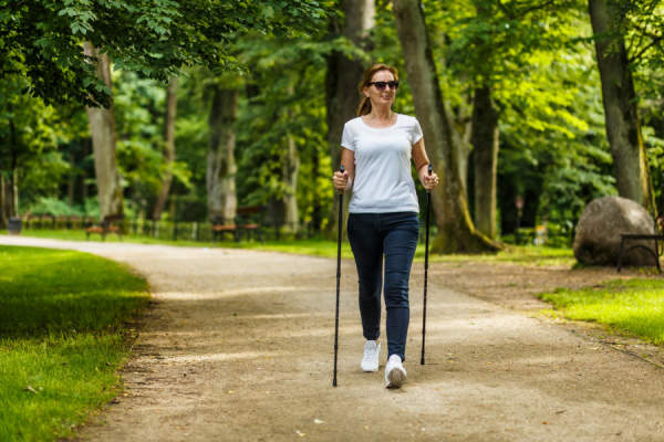 一名中年妇女在城市公园里拄着登山杖行走
