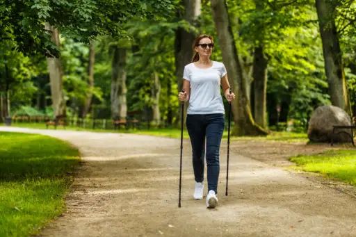 一位中年妇女拄着拐杖在城市公园里散步