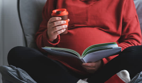 孕妇阅读手里拿着饮料。
