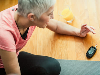 女人检测血糖，同时锻炼，橙汁的玻璃附近。