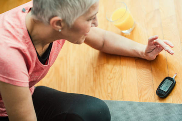 女人检测血糖,同时锻炼,橙汁的玻璃附近。