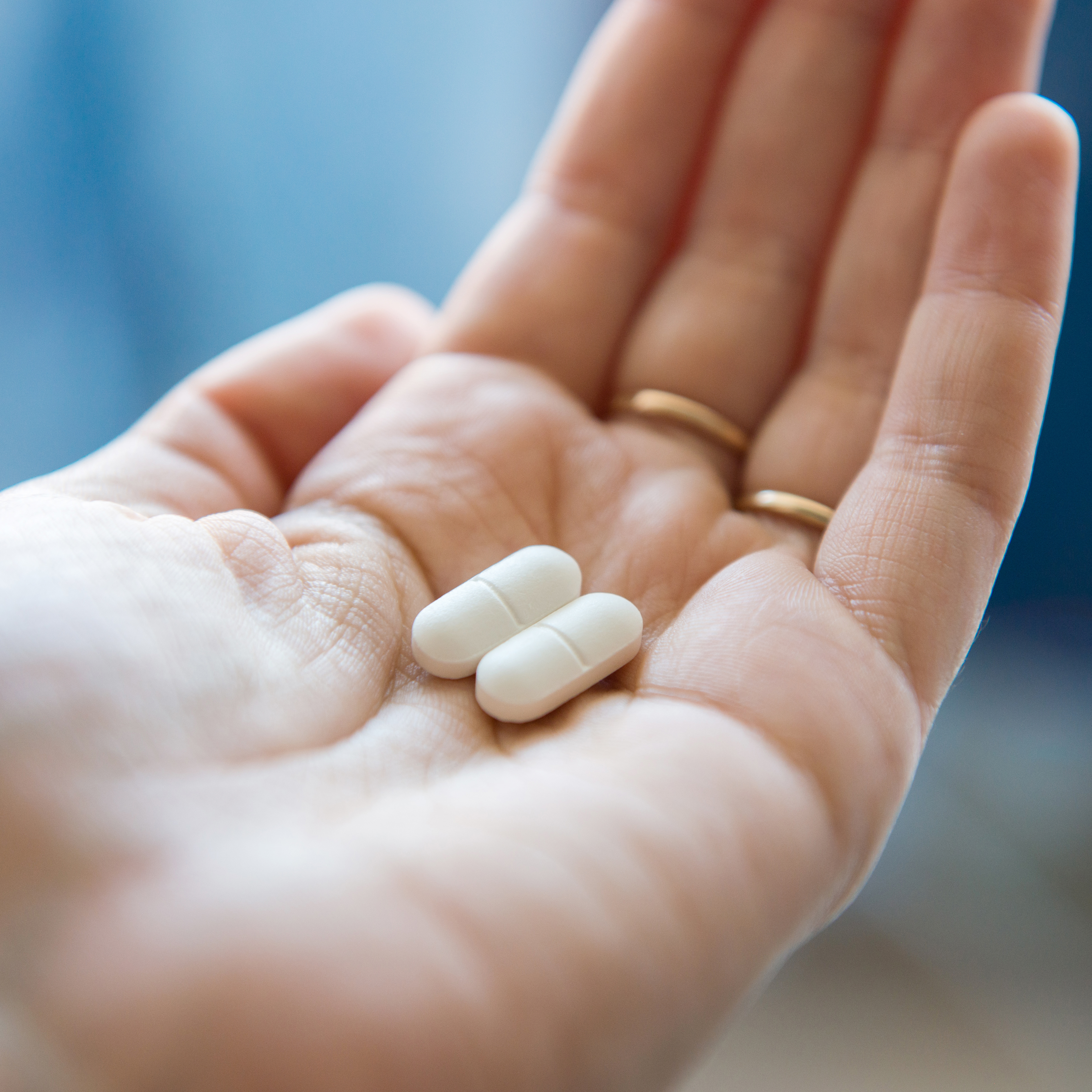 近景的手拿着两个白色的药丸在手掌。