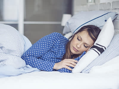 女人穿着长睡衣在床上睡觉。