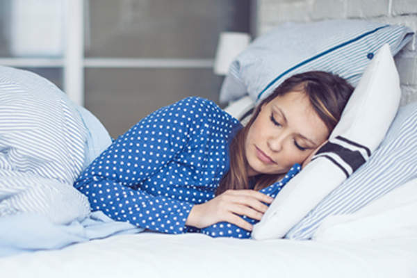 女人穿着长睡衣在床上睡觉。