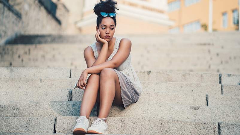 不幸的女人坐在户外的步骤。