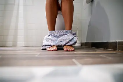 女子的脚在厕所摊位上显示，因为她去浴室溃疡性结肠炎症状。