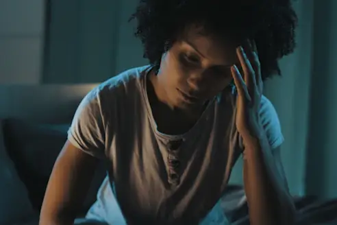A woman sits up in bed at night