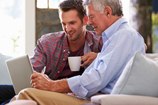 儿子一台笔记本电脑的图像上帮助父亲。